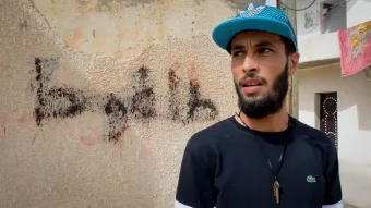 Rapper Mohamed Zorgui steht vor dem Graffiti „Hier wohnt ein Feind des Propheten - Daesh“